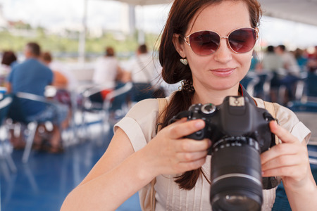 The girl the brunette the photographer in a summer blouse and sunglasses photographs the digital cameraの写真素材