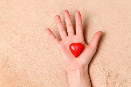 Fingers of hands hold red decorative heartの写真素材