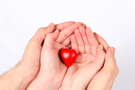 Fingers of hands hold red decorative heartの写真素材