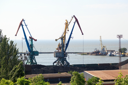 TAGANROG, RUSSIA - June 23, 2016: Operation of the port easel in port against the background of coal and coaches of trainsのeditorial素材