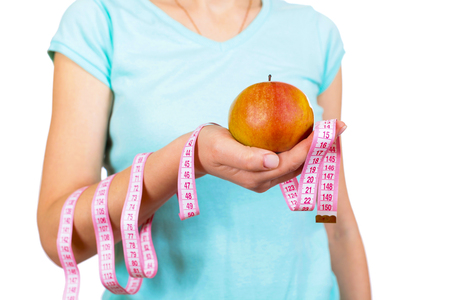 One girl in a t-shirt holds before herself apple and meter in hand, a close up, on the isolated white backgroundの写真素材