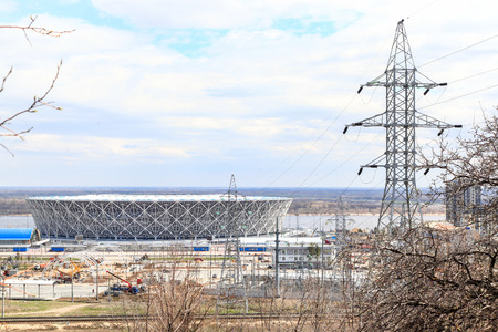 VOLGOGRAD, RUSSIA - April 21, 2018: A high-voltage support of the power line, behind him the Arena stadiumのeditorial素材