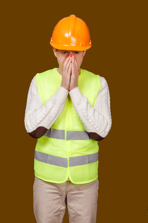 the adult man in a construction helmet and a vest sneezesの写真素材