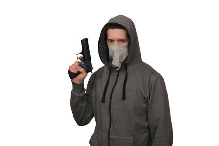 The man in a sports jacket and in a mask on a face shoots with the gun. A white background, a...