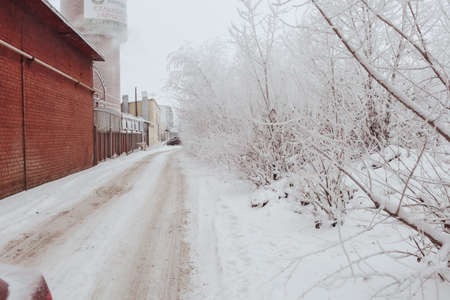 The winter dirt rural road in snow along a red brick wallのeditorial素材