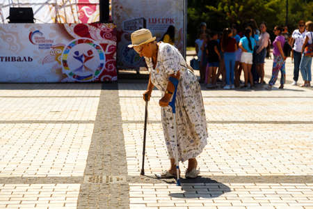 KERCH, RUSSIA - June 30, 2019: Old lady walks with a cane down the streetのeditorial素材