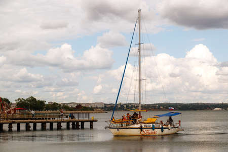 KERCH, RUSSIA - June 29, 2019: a yacht with a sail in the sea berths to the shore. Side viewのeditorial素材