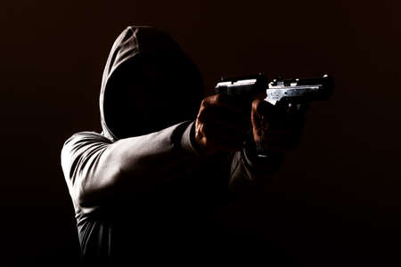 dangerous hooded man threatens with a shot from two pistols in his hands, isolated, one