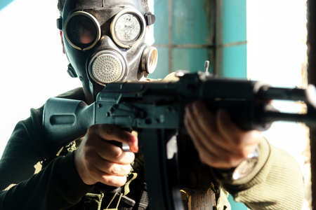 A military man in a black gas mask aims to point his automatic weapon at the cameraの写真素材