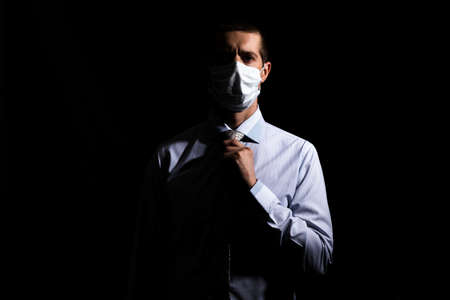 business successful man in a medical mask, slave and tie, portrait. on black, isolatedの写真素材