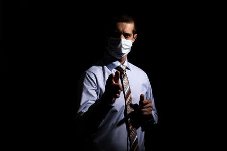 businessman, a successful man in a medical mask, a slave and a tie, shows his index finger. on black, isolatedの写真素材