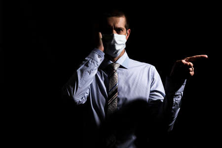 businessman, a successful man in a medical mask, a slave and a tie, shows his index finger. on black, isolatedの写真素材