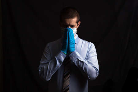 business man masked doctor prays, on a dark background, isolatedの写真素材