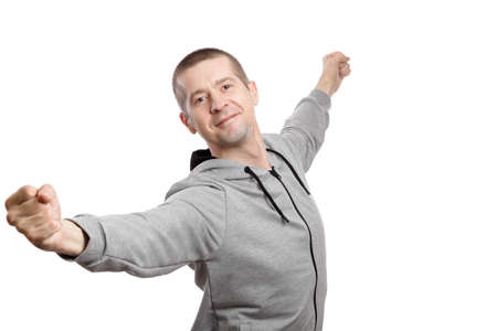 Smiling joyful man, celebrating victory, hands to top, dressed in a sports jacket with a hood, gesture OK okey good. Isolated, on whiteの写真素材