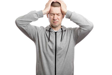 repentant or with a headache, the man clutched his head with both hands. Dressed in sportswear. Isolated, on whiteの写真素材