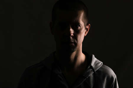 dark silhouette of a man on a black background, a glance at the camera. Dressed in sportswear. Isolated, on whiteの写真素材
