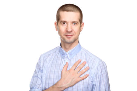 Joyful man in love in a classic blue shirt Put his hand on heart. look into the camera. Isolated, on whiteの写真素材
