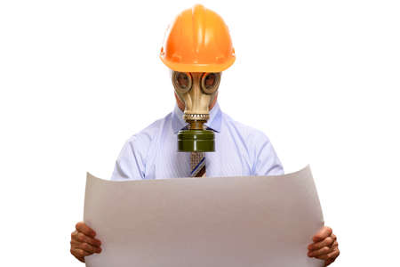 An engineer, protected in a gas mask, in a helmet, shirt and tie, looks into the working drawings. Isolated, on whiteの写真素材