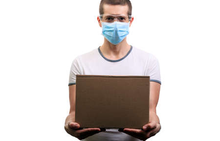Courier in medical mask and glasses holds a cardboard box in his hands