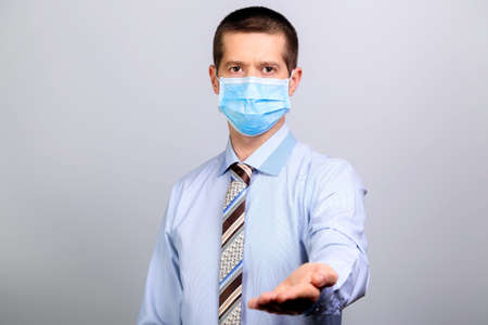 Man in medical mask, shirt, tie extends his handの写真素材