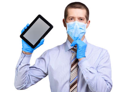 Man in medical mask, shirt, tie, rubber gloves, holding tablet computer, looking into camera,...