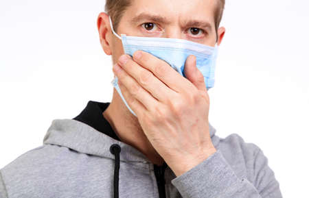 Sports the man in a hood, a medical mask on the person, coughs, isolated, white, close upの写真素材