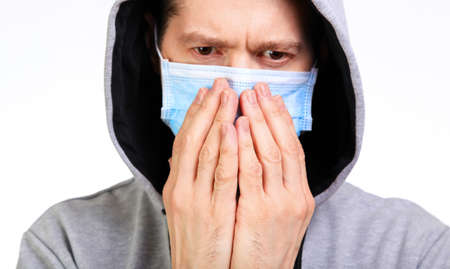 Sports the man in a hood, a medical mask on the person, coughs, isolated, white, close upの写真素材