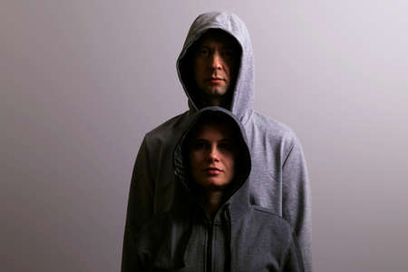 Man and woman in hoods stand by, low key, dark backgroundの写真素材