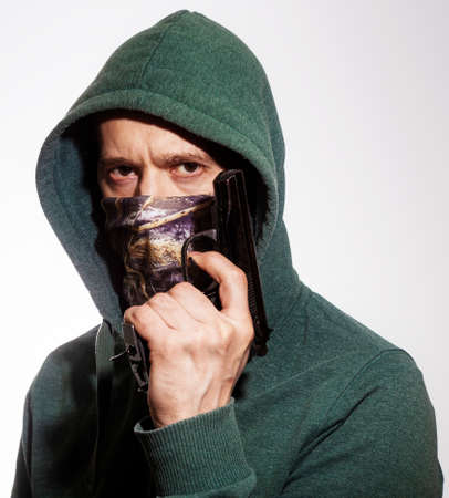 A man wearing a mask holds a gun in his handの写真素材