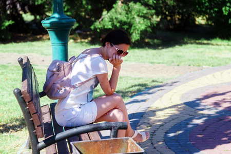 Girl misses on bench in summer in parkの写真素材
