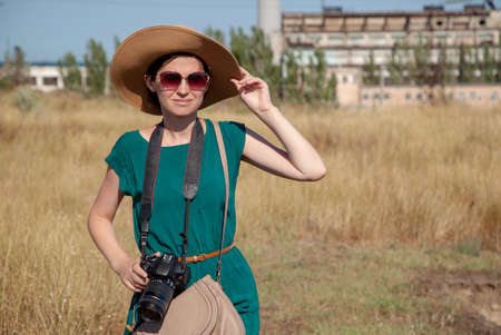Portrait of a girl with a camera in a hat and a dressの写真素材