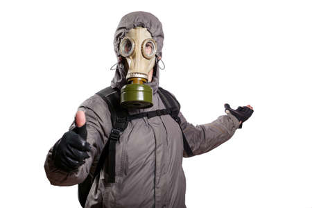 An isolated shot of a man dressed in a gas mask, a hooded jacket, a backpack, shows a gesture of okey, the other hand stretched back indicating the direction, looking into the camera. On a white isolated background, the studioの写真素材
