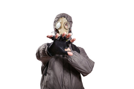 An isolated shot of a man dressed in a gas mask, a jacket with a hood, a backpack, out of fear, defending himself, stretched out his arms in front of him. On a white isolated background, the studioの写真素材
