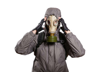 An isolated shot of a man dressed in a gas mask, a jacket with a hood, a backpack, holding his fingers at the temple, a headache. On a white isolated background, the studioの写真素材