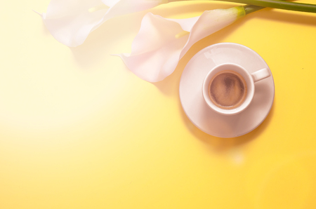 White calla flower with coffee isolated on yellow background. Morning. Flat lay. Top view. Copy spaceの写真素材