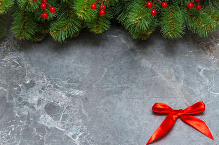 green spruce branches with mistletoe and red bow on gray marble background.の写真素材