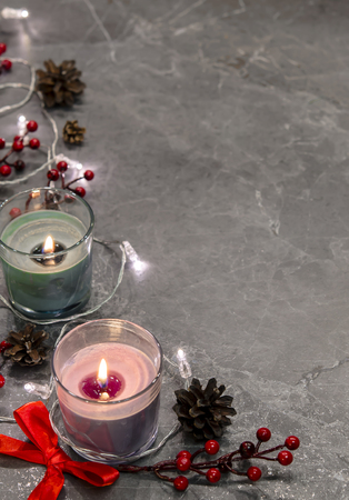 burning candles with garland, mistletoe, pine cones, red bow on a gray marble background.の写真素材