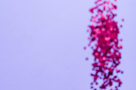 Holographic hearts on blurred trendy purple background. Festive backdrop. Top view. Copy spaceの写真素材