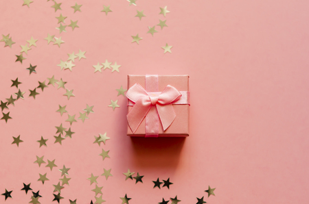 Gift box with holographic golden stars. Living Coral - Color of the Year 2019. Festive backdrop. Top view. Copy spaceの写真素材