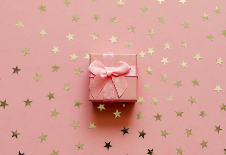 Gift box with holographic golden stars. Living Coral - Color of the Year 2019. Festive backdrop. Top viewの写真素材