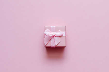 Pink gift box with bow on pink pastel background. Festive backdrop. Top view. Copy spaceの写真素材