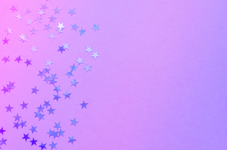 Holographic stars on trendy pink background. Festive backdrop. Top view. Copy spaceの写真素材