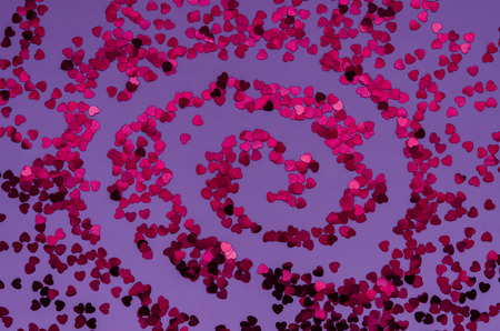 Holographic red hearts on trendy purple background spiral shaped . Festive backdrop. Top viewの写真素材