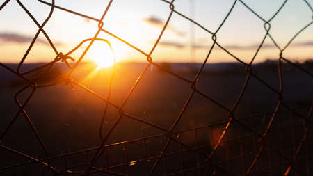 Metal fence with the sunset in the backgroundの写真素材