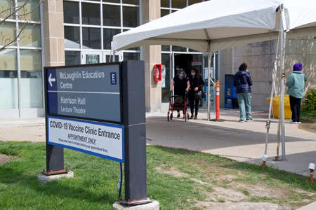 Toronto, Ontario, Canada - 04/27/2021: People line up in the entrance to the COVID-19 Vaccination Clinic ( Sunnybrook Hospital ) in Toronto, Canada.のeditorial素材