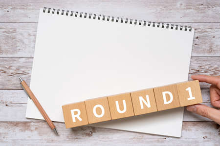 Wooden blocks with "ROUND1" text of concept, a pen, and a notebook.の写真素材