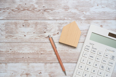 A white calculator, a pen, and a house toy.の写真素材