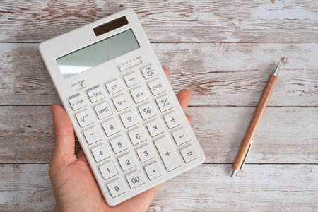 Calculator in hand on wooden background. Business and finance conceptの写真素材