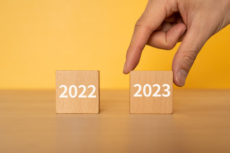 Wooden blocks with "2022" and "2023" text of concept and a human hand.の写真素材