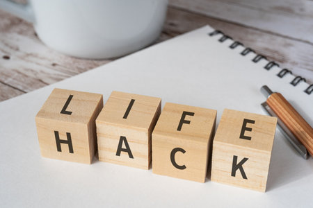 Wooden blocks with "LIFE HACK" text of concept, a pen, a notebook, and a cup.の写真素材